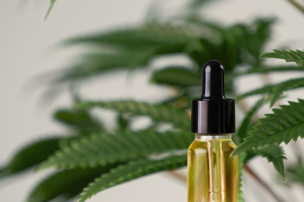 Closeup image legalized CBD oil in bottle with dropper lid with leafs backdrop