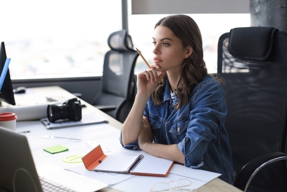 Concentrated young woman writing something down while working in the office.