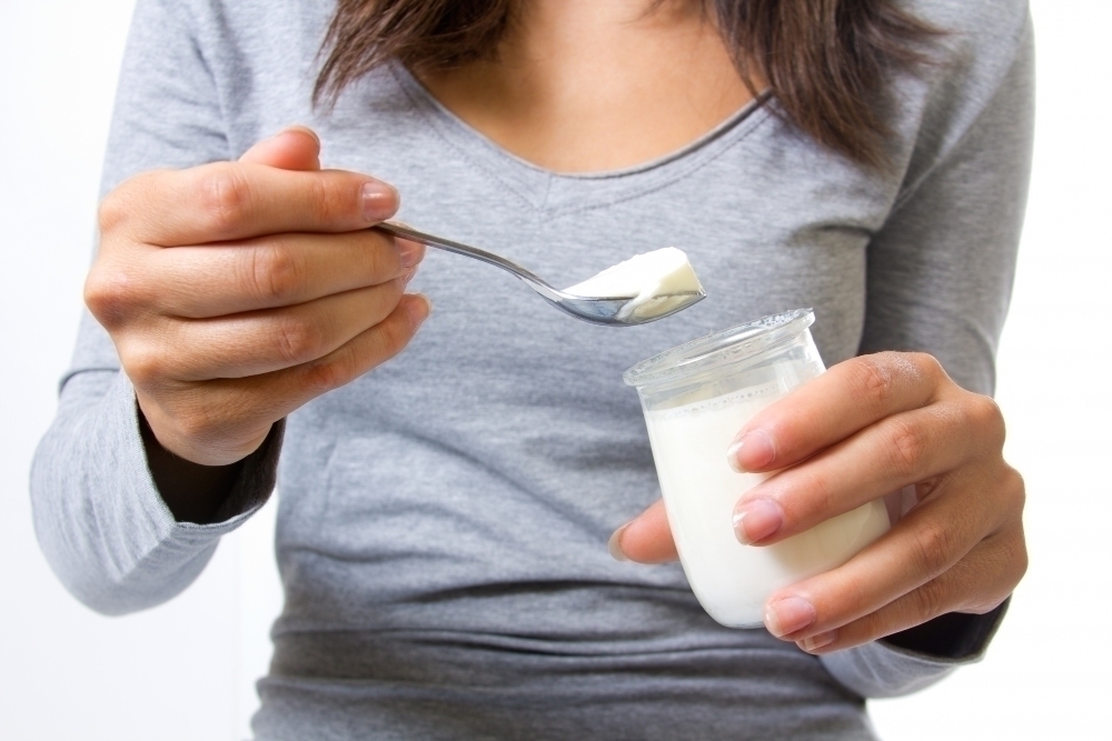 Faceless female eating yogurt