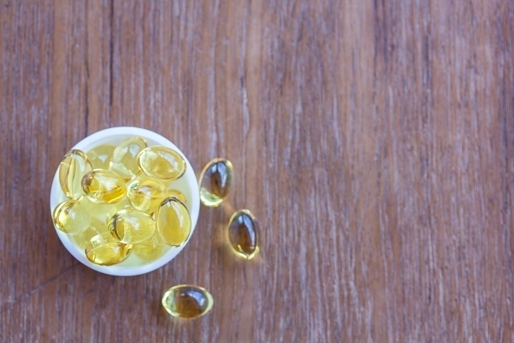 Omega 3 fish liver oil capsules in wooden background