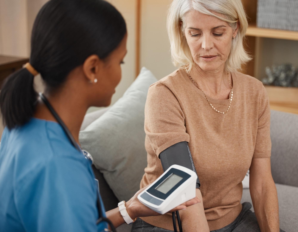 People nurse and blood pressure machine in cardiovascular healthcare or wellness with happiness Mature woman medic and check for support medicine or results as professional in clinic or hospital