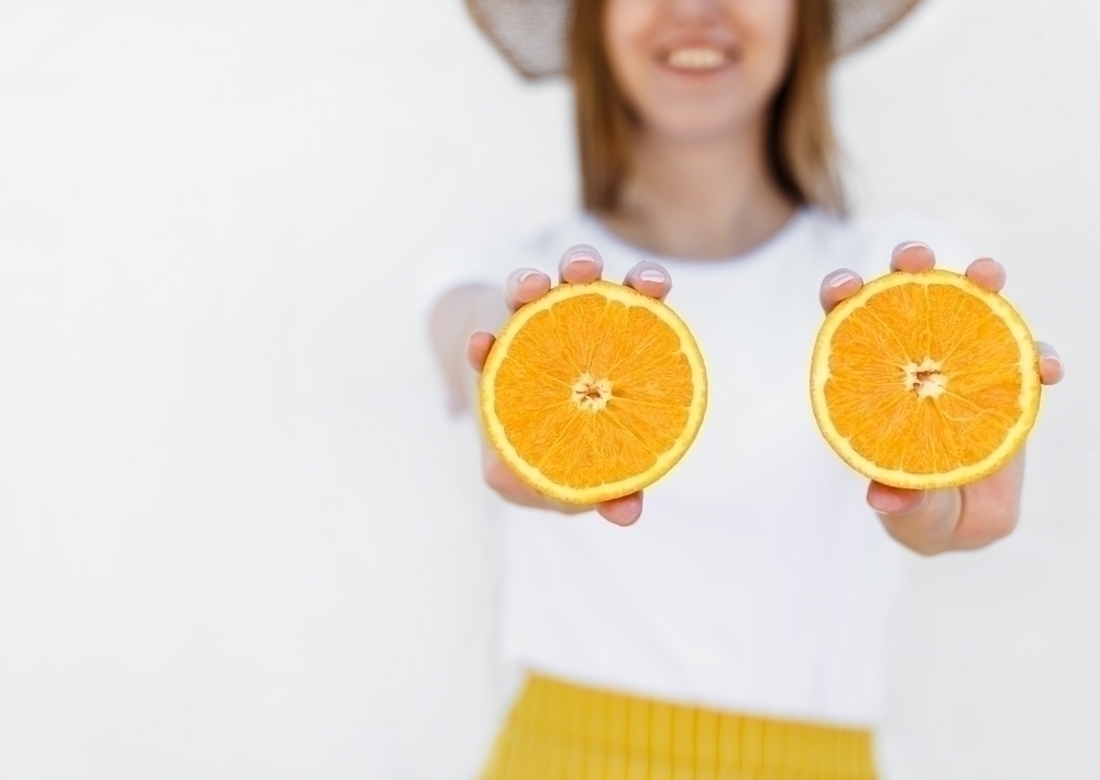 Womens hands hold a juicy half orange isolated on white