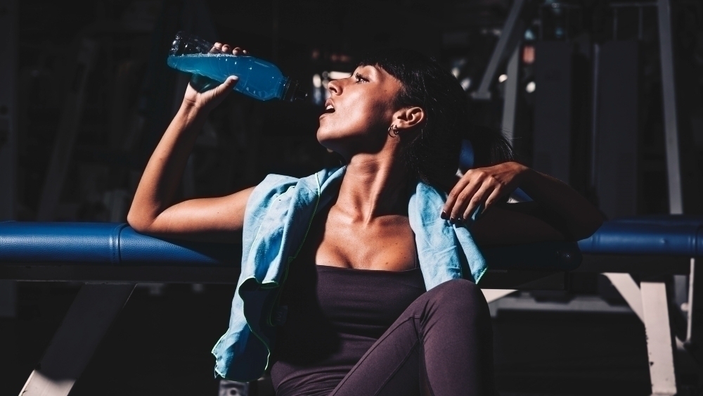 kvinna dricker clear whey pa gym
