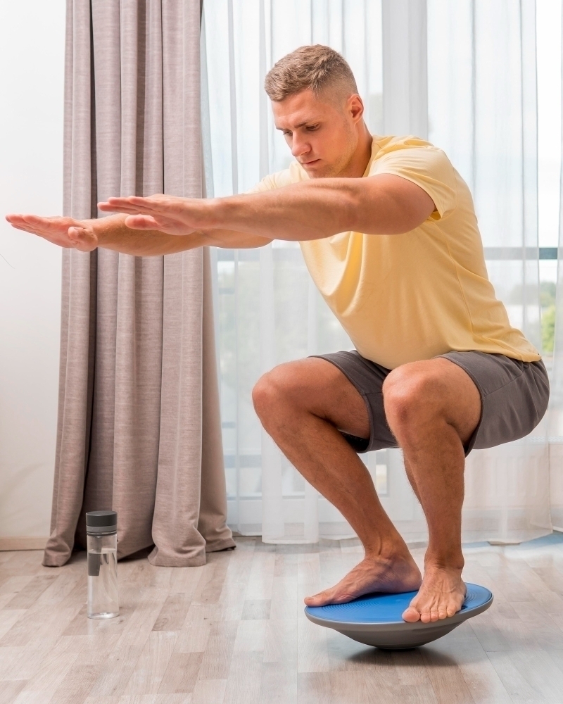 side view man training home using bosu ball