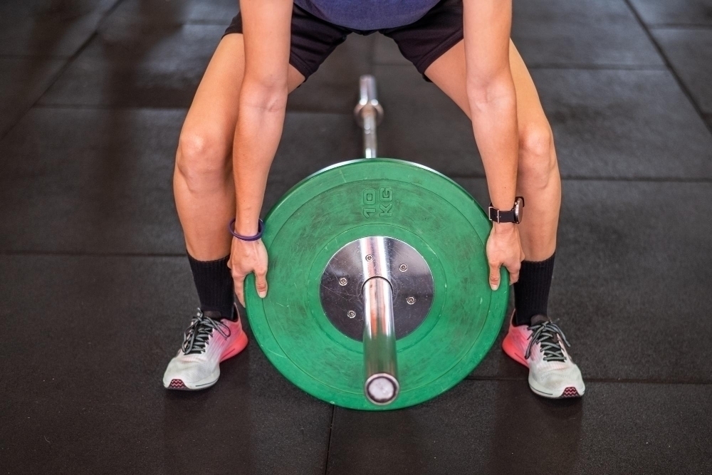 unrecognizable sportsman putting heavy discs barbell while preparing weightlifting workout