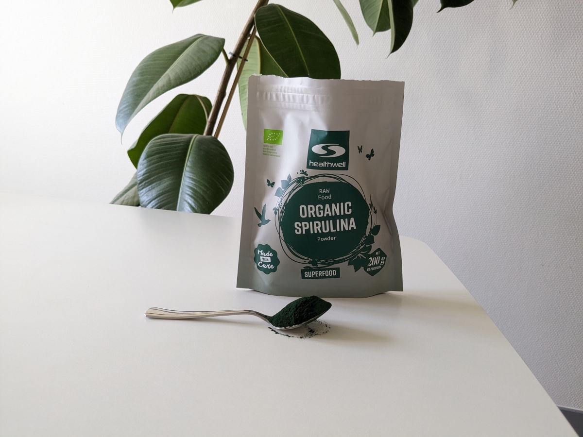 Healthwell Spirulina EKO på bord med sked pulver, egen testbild