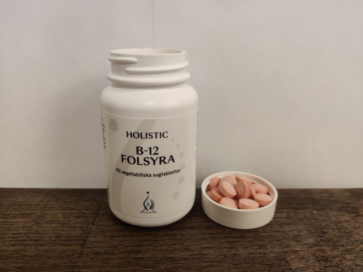 Holistic B12 Folsyra på träbord med tabletter bredvid eget foto