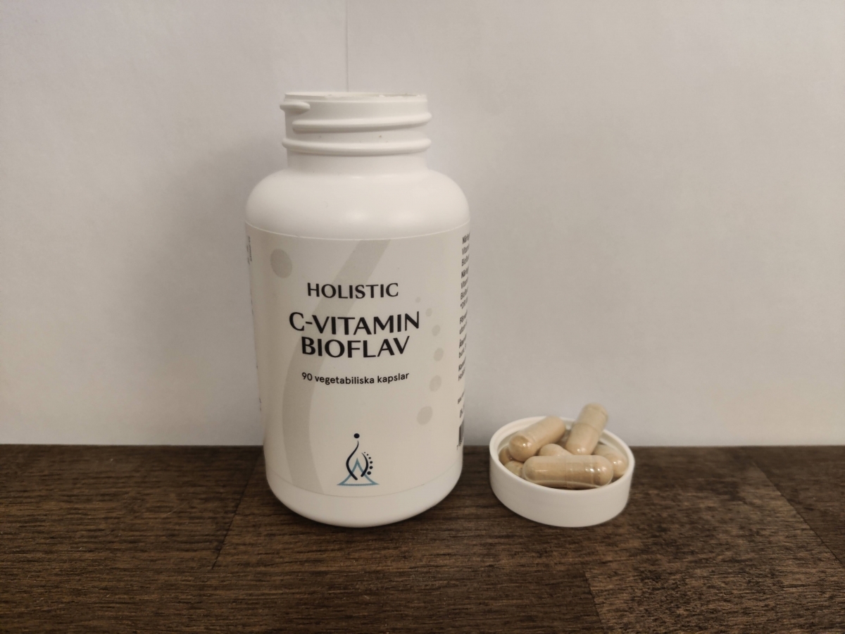 Närbild på Holistic C-Vitamin Bioflav med kapslar bredvid