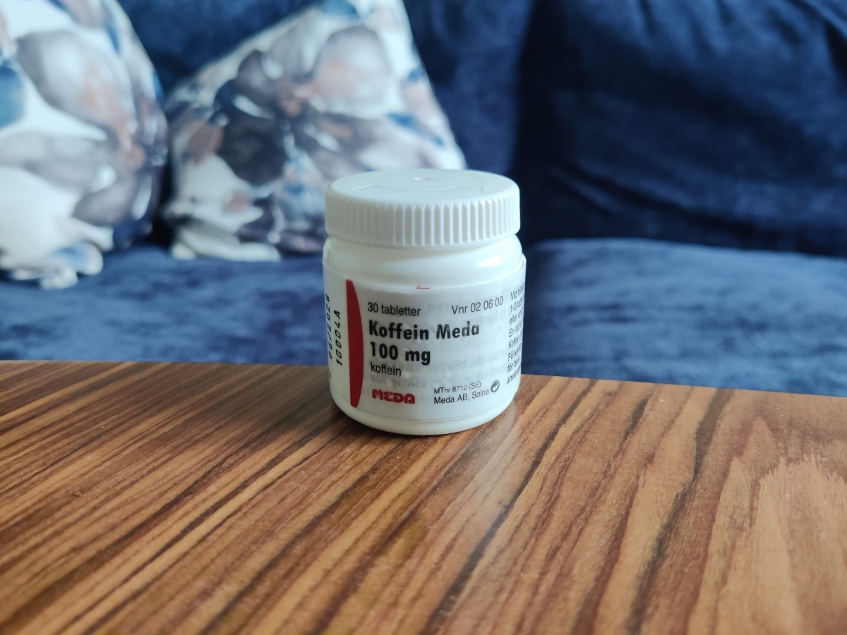 Meda Koffein 100 mg i liten vit burk på soffbordet, foto av oss