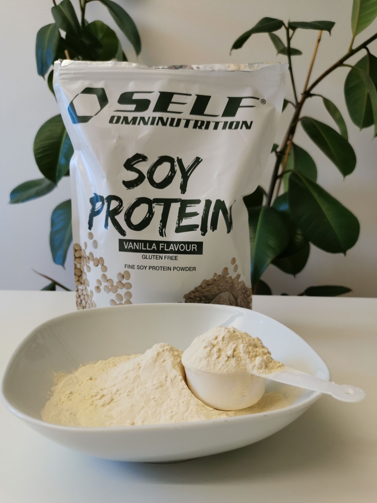 Finmalet sojaprotein i skål med skopa framför förpackningen