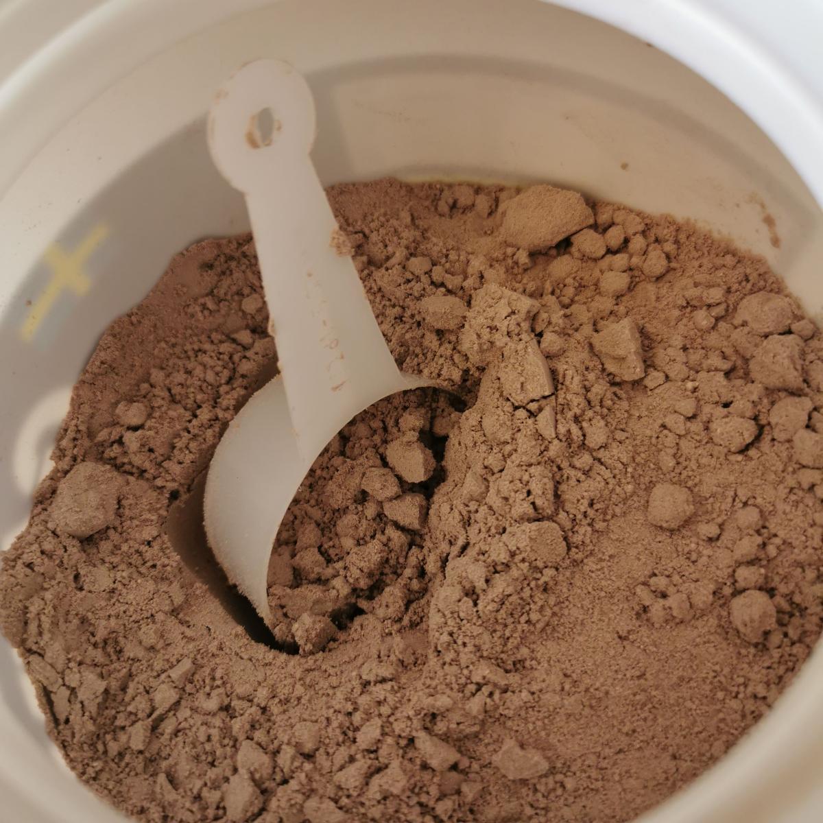 Öppnad burk med chokladpulver och skopa från Better You Gainer