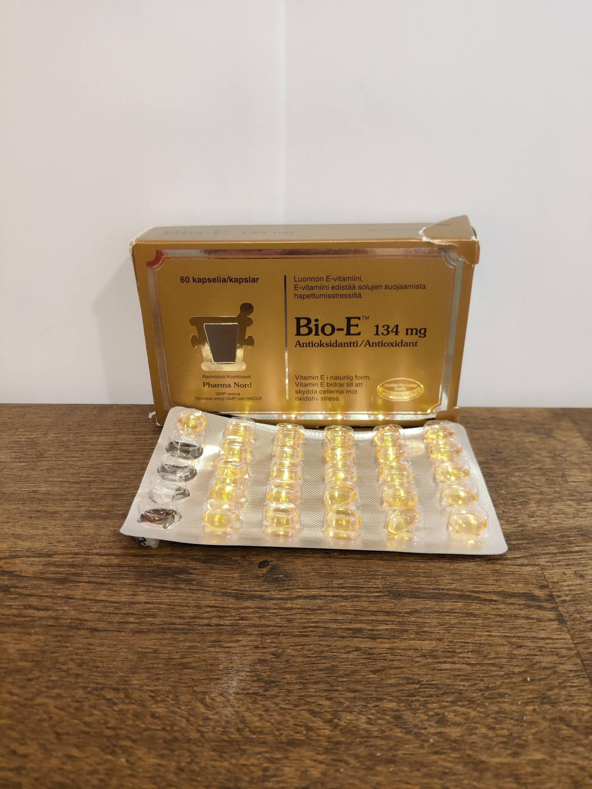 Bio-E-Vitamin på träbord med öppnat blister, flera kapslar redan använda