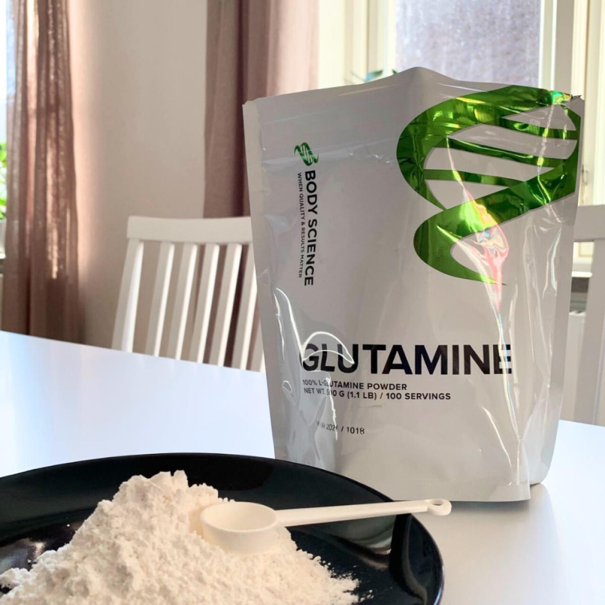 Glutaminpulver på tallrik med egen skopa och förpackningen i bakgrunden, vårt foto
