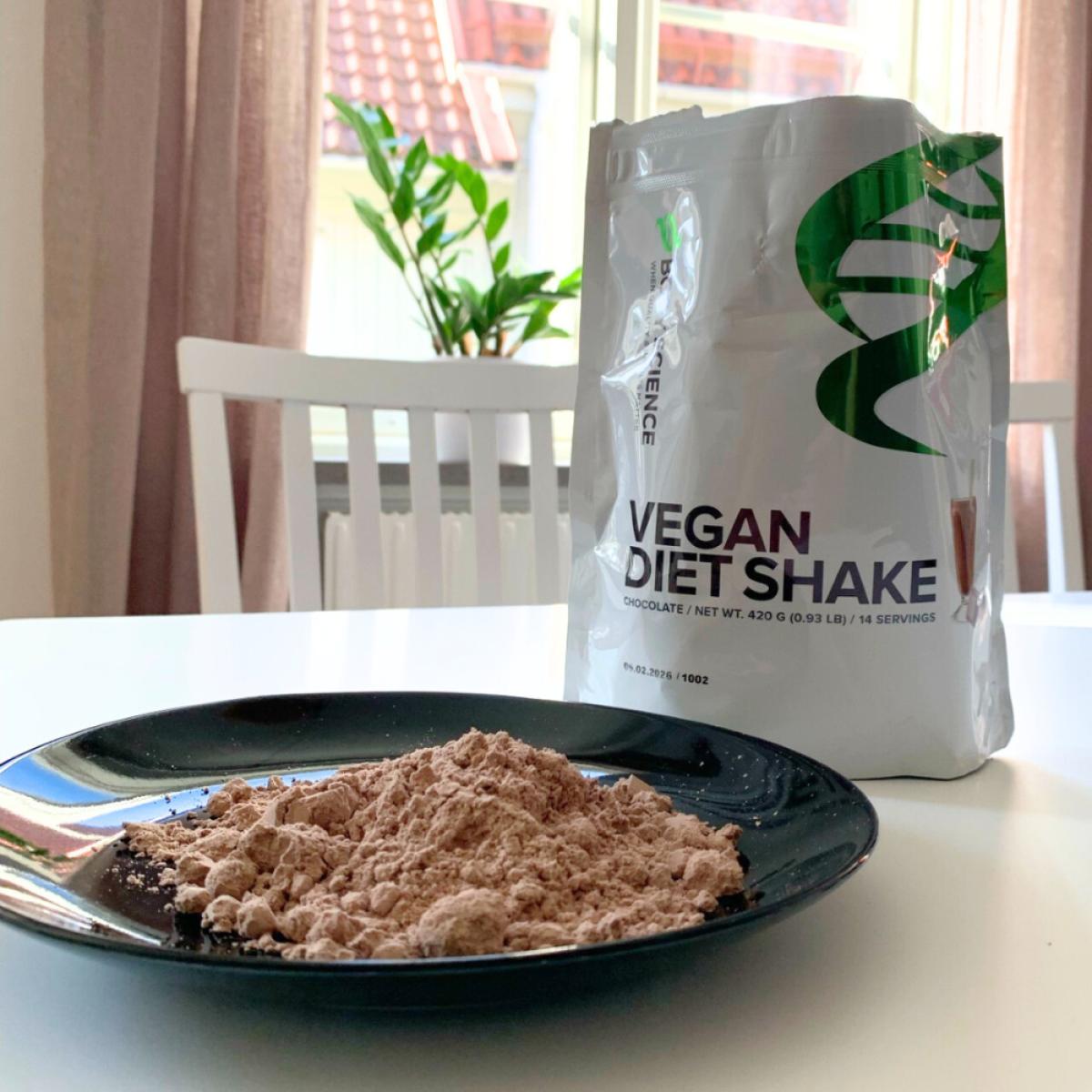 Portion av pulver på tallrik med påsen bakom, Body Science Vegan Diet Shake