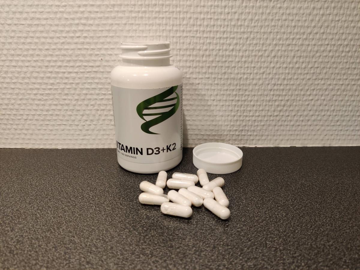 Body Science Vitamin D3+K2 med utspridda kapslar på bänkskiva, foto taget av oss under testet