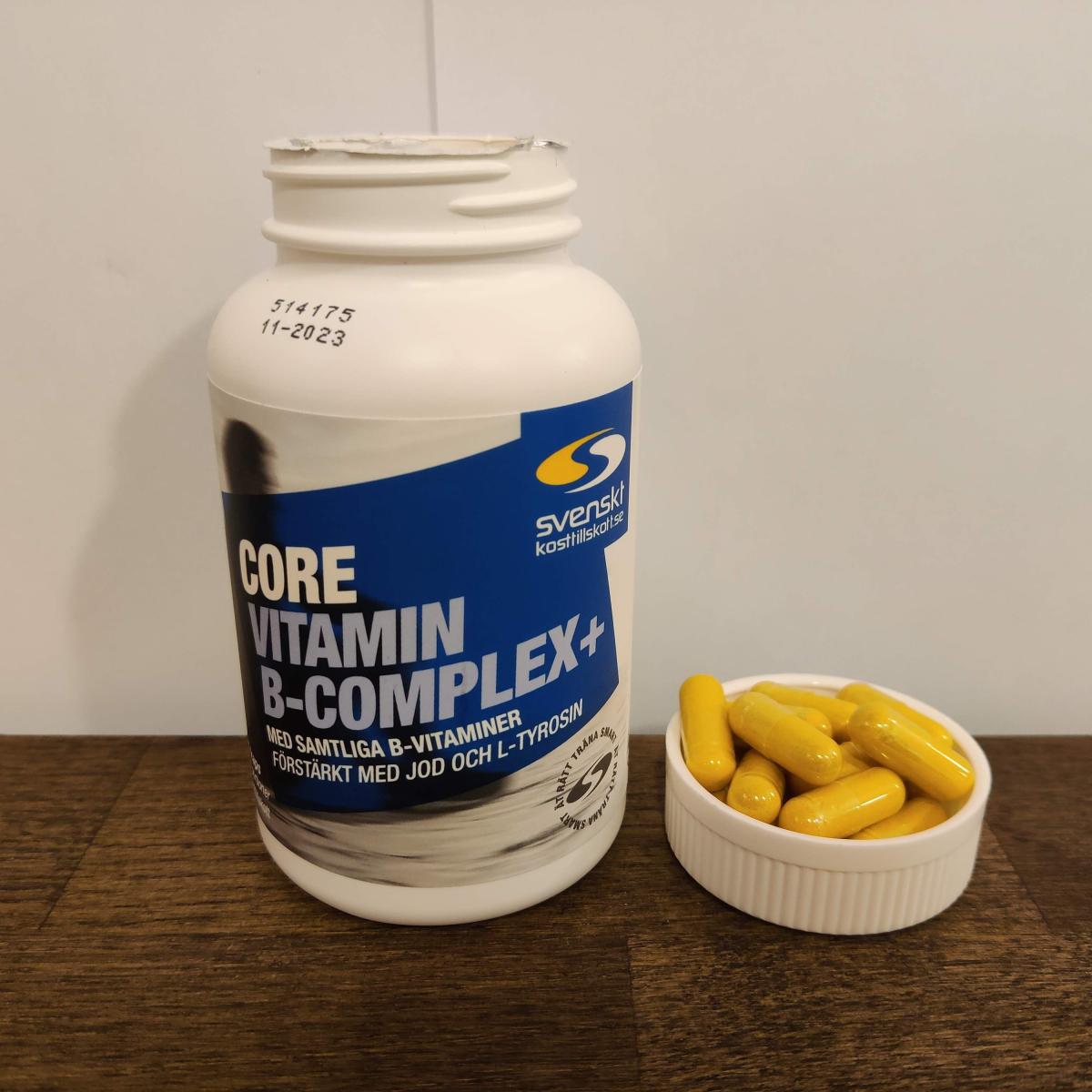 Närbild på Core B-Complex och kapslar i locket på träbord, taget av oss