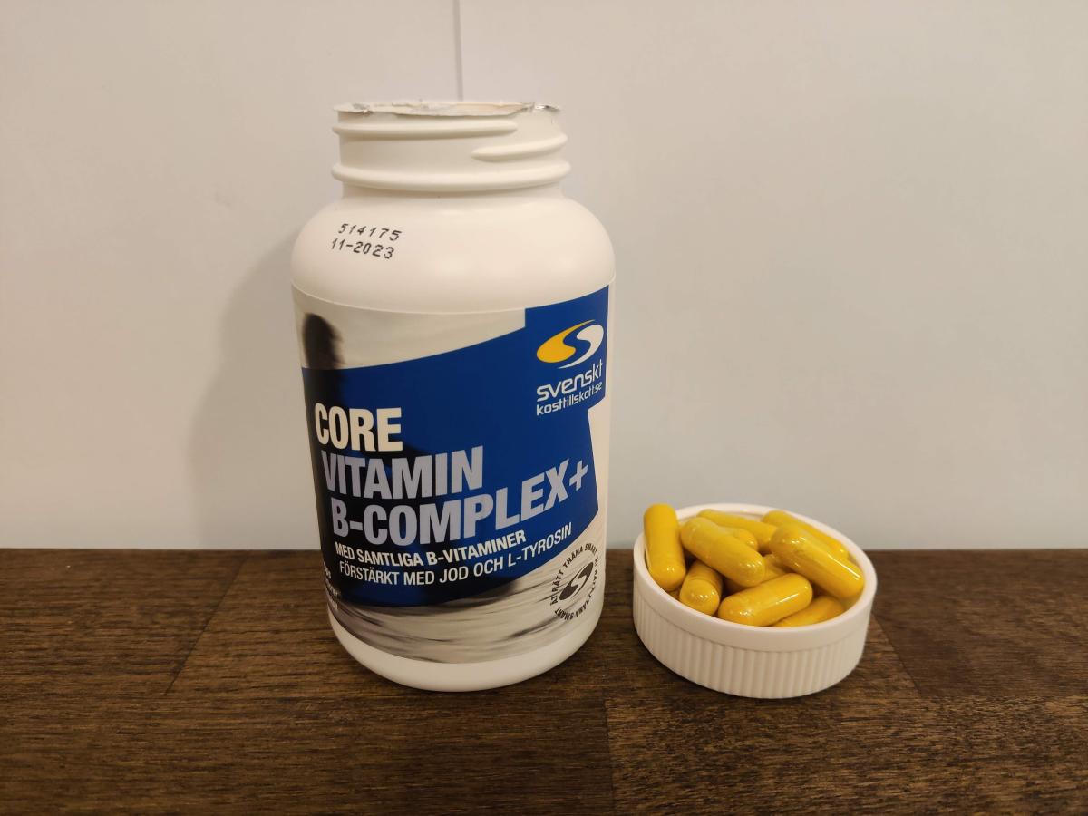 Närbild på Core B-Complex och kapslar i locket på träbord, taget av oss