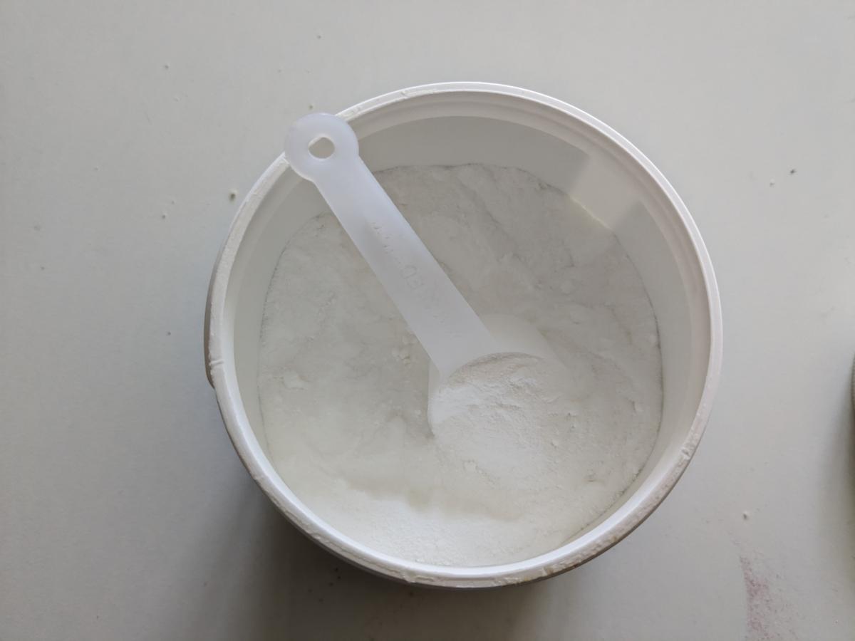 Öppnad burk Core Creatine Pro med skopa i mjölfint pulver fotad i vårt test