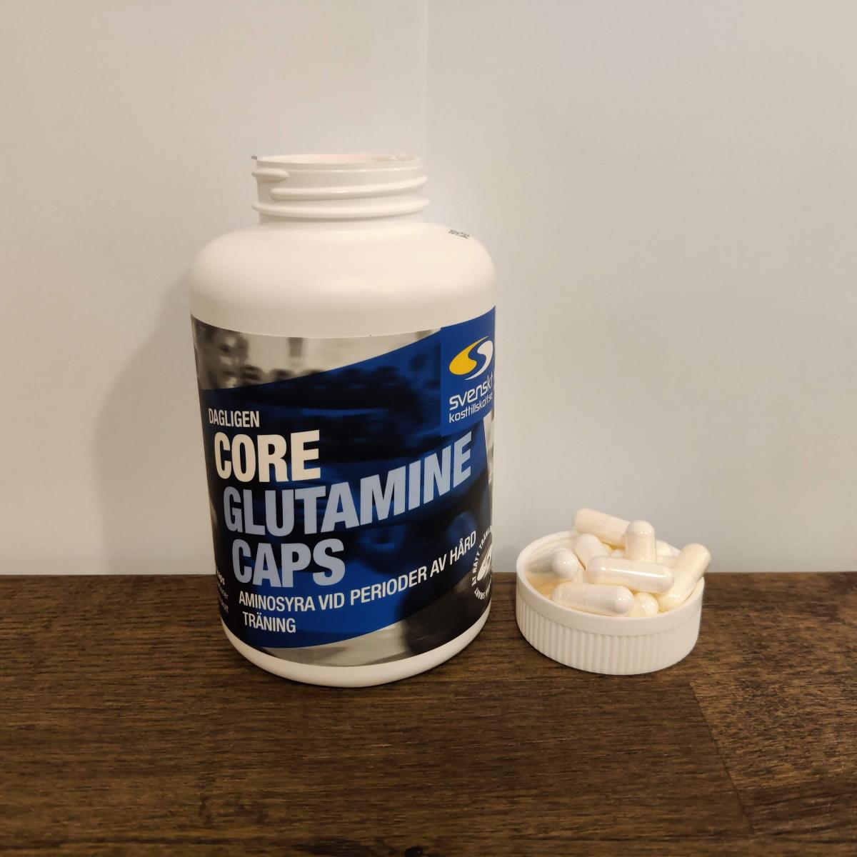 Core Glutamine Caps med kapslar bredvid locket i varm inomhusbelysning