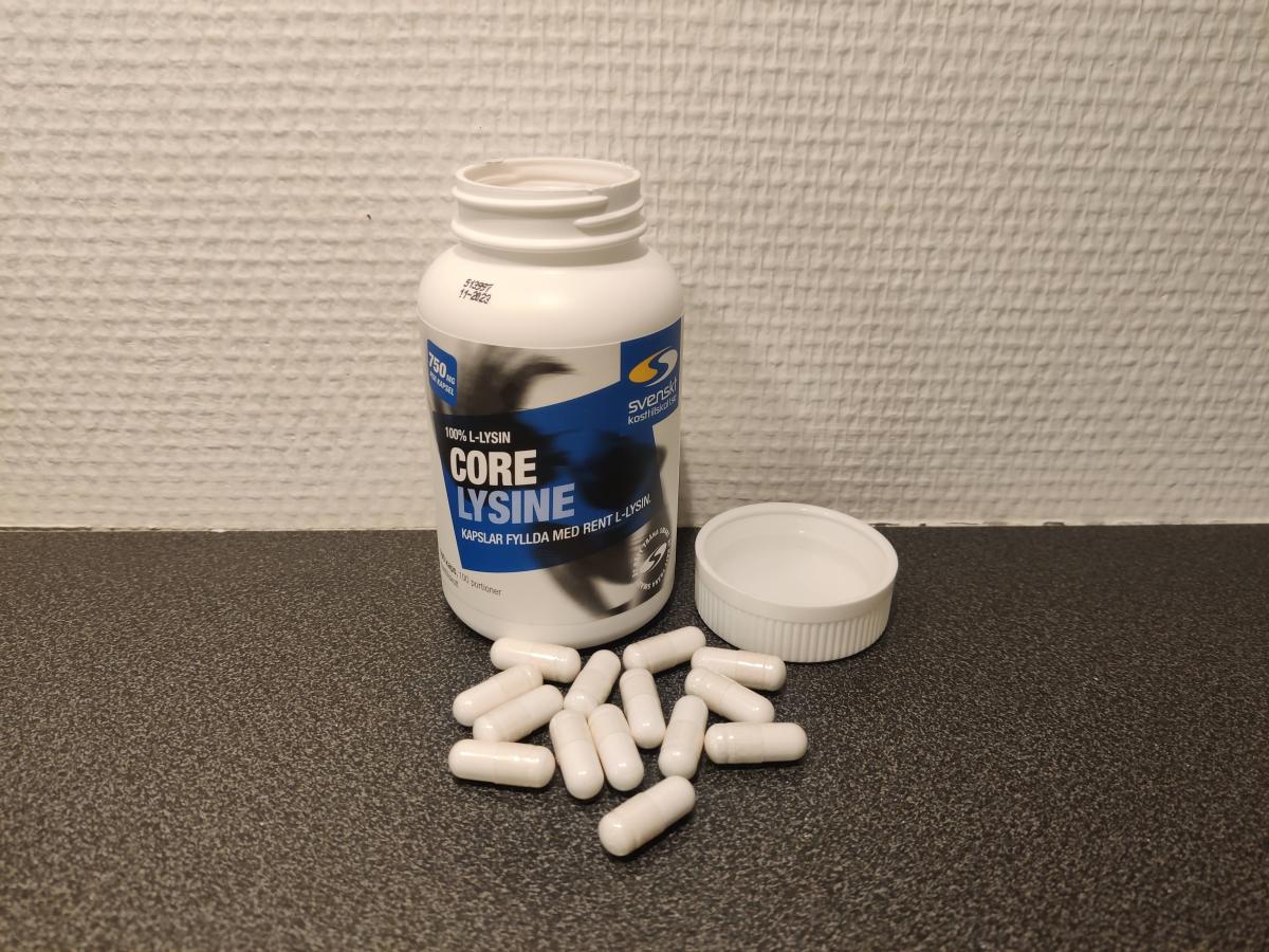 Öppen Core Lysine med kapslar på mörk bänkskiva, fotograferad av oss