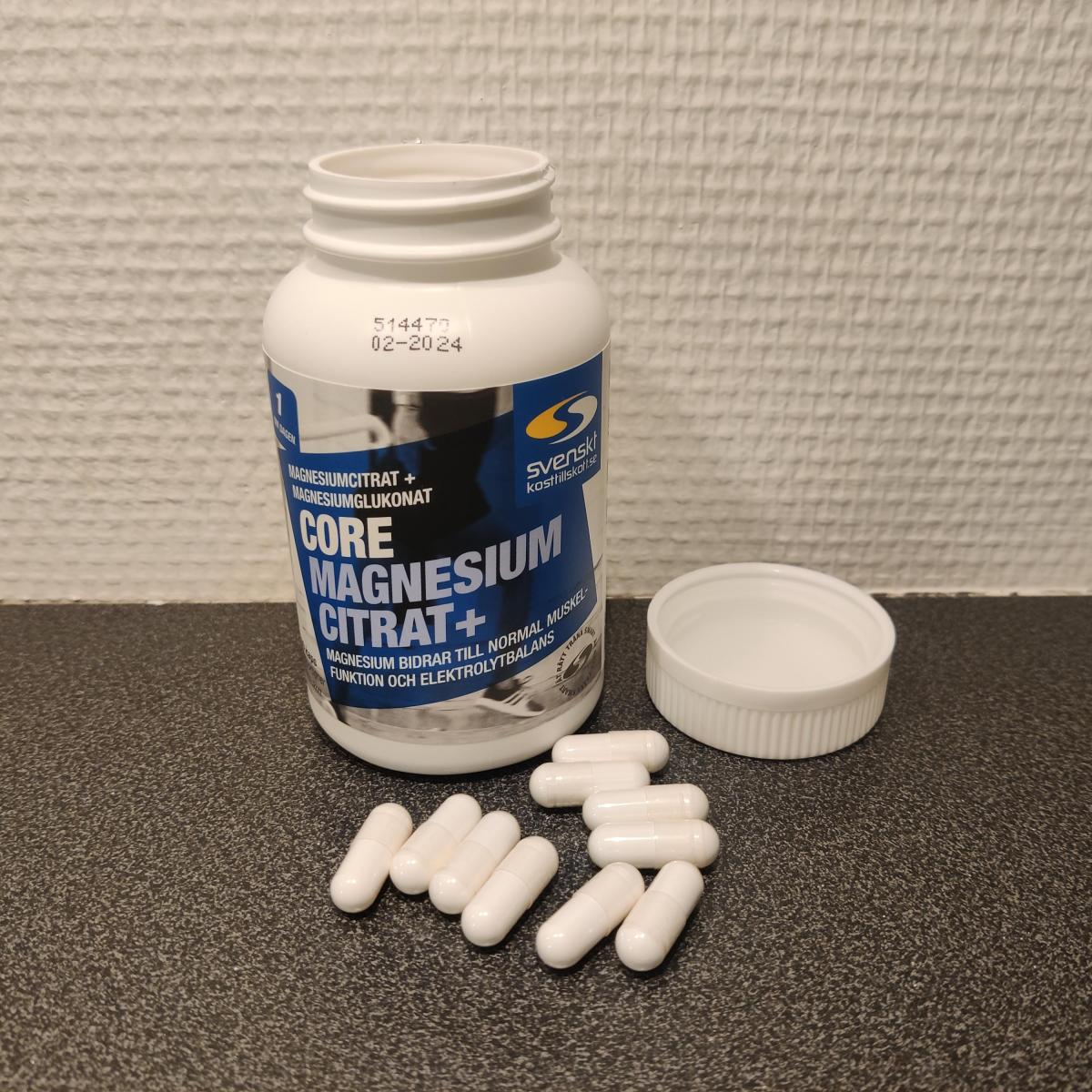 Core Magnesium Citrat på träbord med kapslar i locket, fotograferat av oss