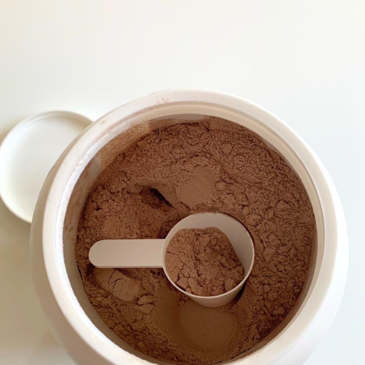 Öppen burk med finmalt chokladpulver och skopa i Core Protein Pro