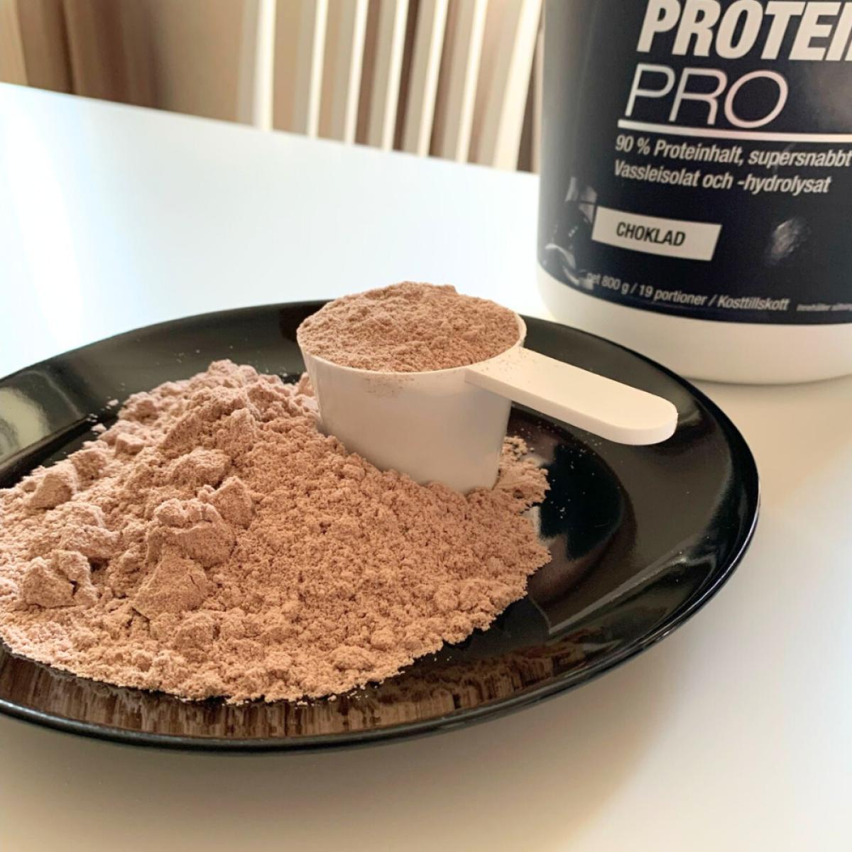 Core Protein Pro uppmätt pulver på svart fat med skopa
