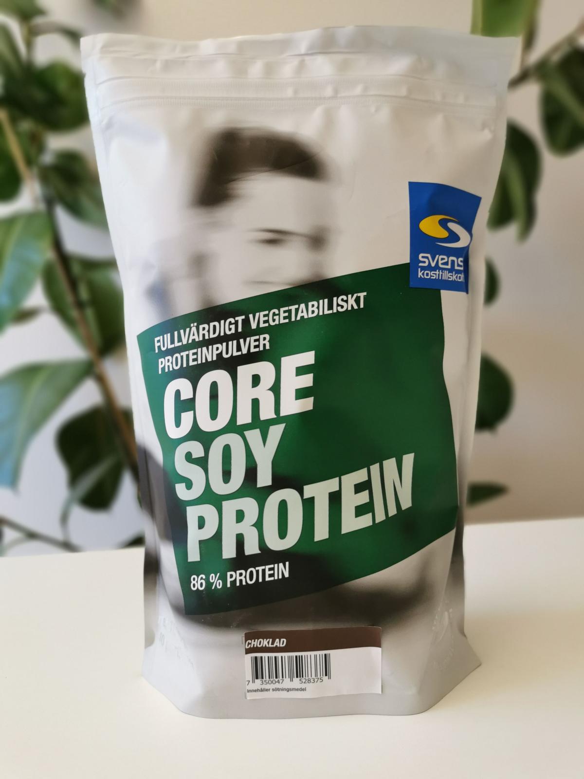 Core Soy Protein choklad framifrån i dagsljus bredvid grön växt, fotad av oss