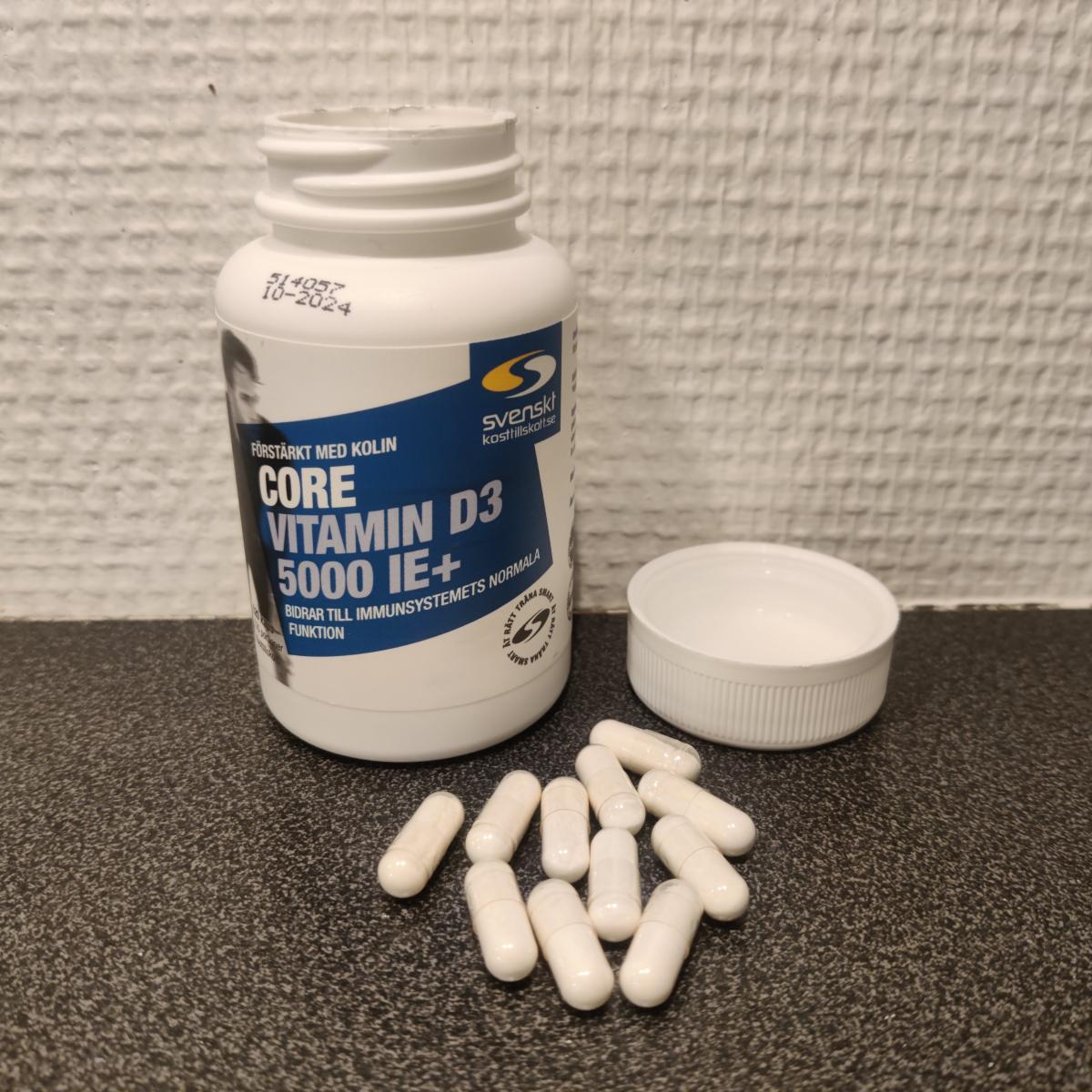 Core Vitamin D3 5000 IE+ på träbord med kapslar intill, foto från vår recension