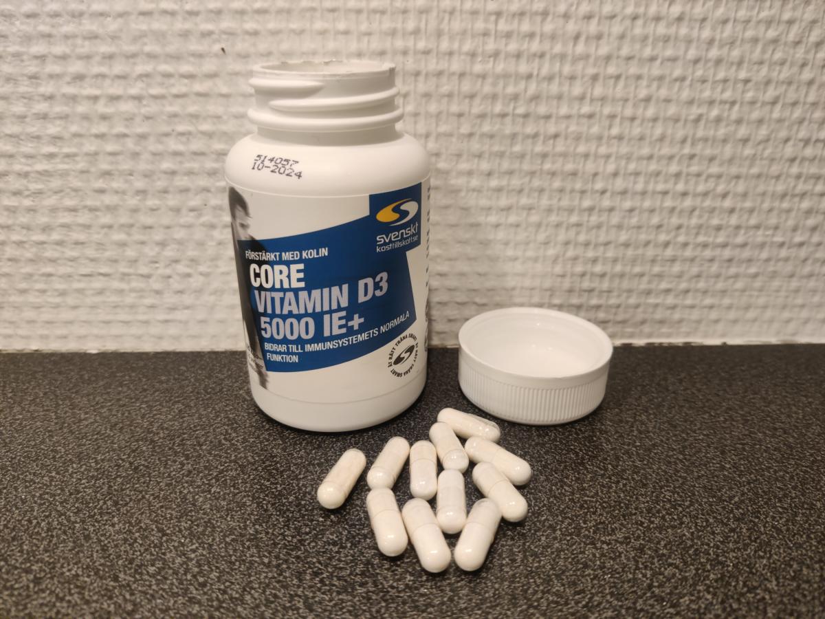 Core Vitamin D3 5000 IE+ öppnad burk med vita kapslar på bänkskiva, fotograferad av oss under testet