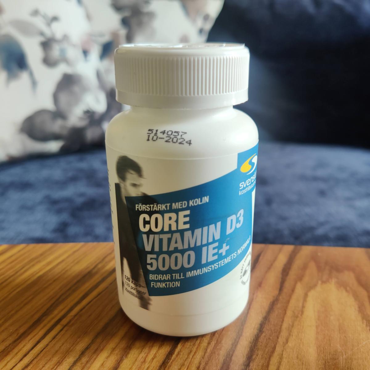 Core Vitamin D3 med två kapslar bredvid på tyg, tagen i vardagsrummet