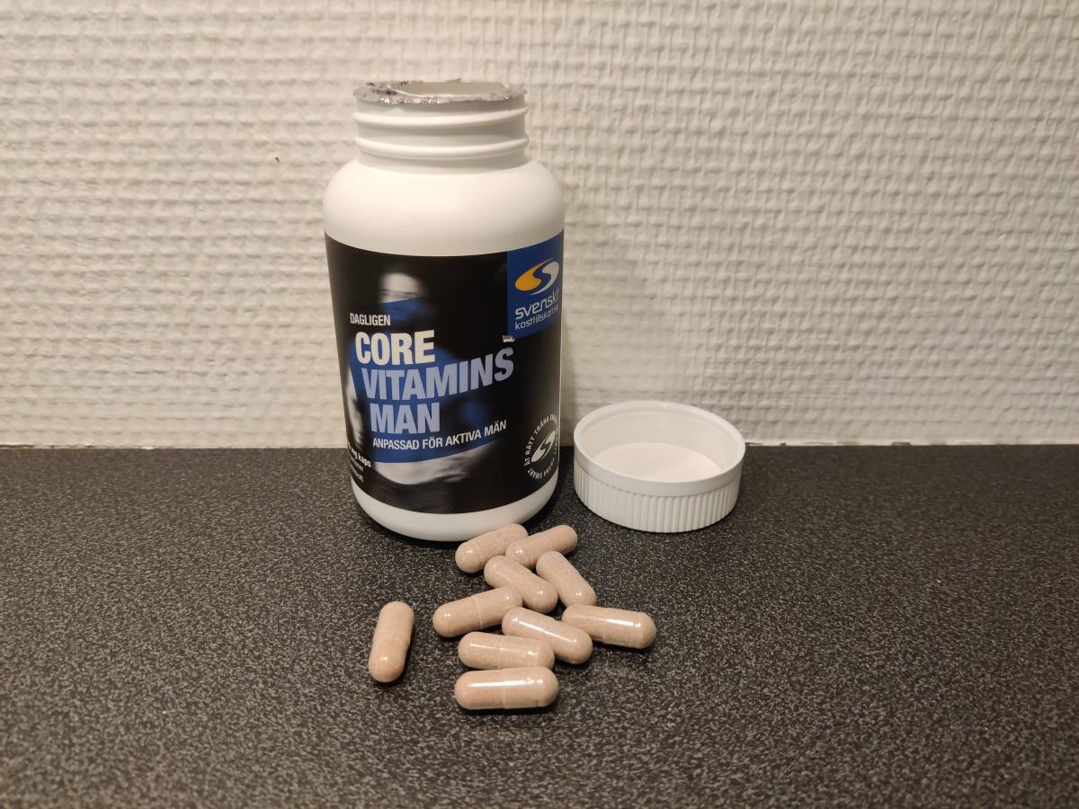 Core Vitamins Man med öppnad burk och kapslar på bänken, foto taget av oss