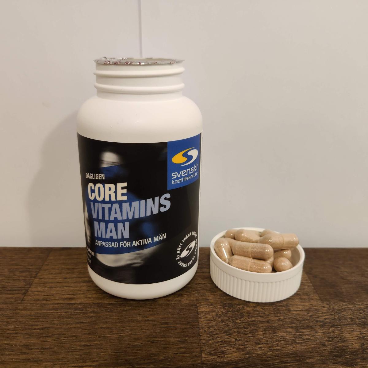 Core Vitamins Man på träskiva med några kapslar i locket, vårt foto