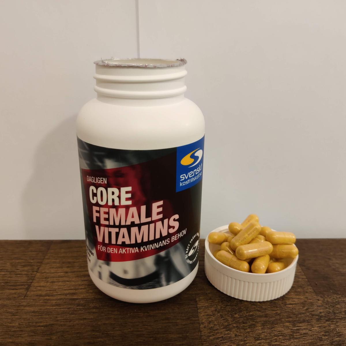 Core Vitamins Woman på träbord med dagens kapslar bredvid