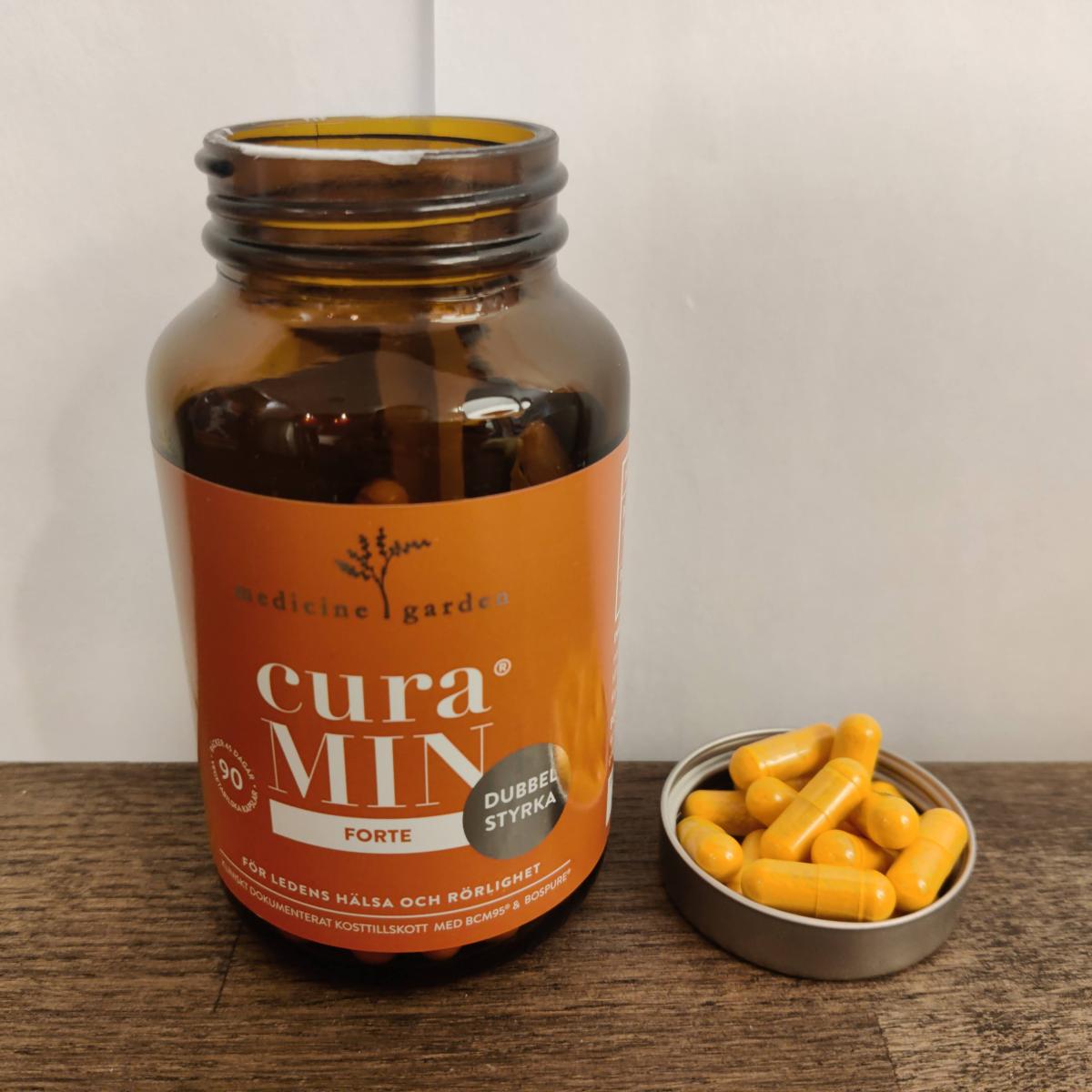 Närbild på MedicineGarden CuraMIN-burk och upphällna kapslar, tagen av oss