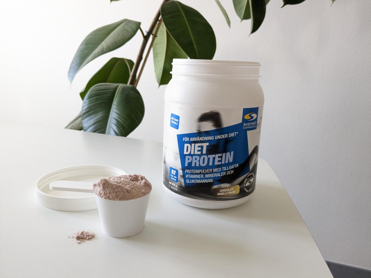 Diet Protein burk och uppmätt skopa på bord i dagsljus, tagen av oss