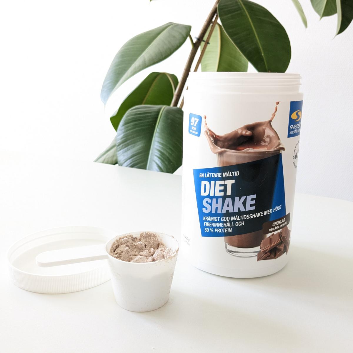 Diet Shake choklad med skopa på bord i dagsljus, fotad av oss under testet