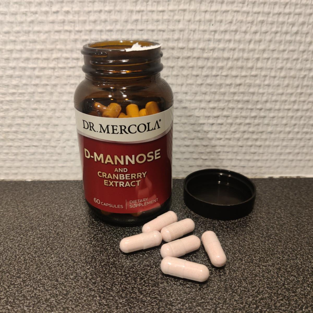 Dr Mercola D‑Mannose kapslar bredvid burken på träbord i mjukt dagsljus