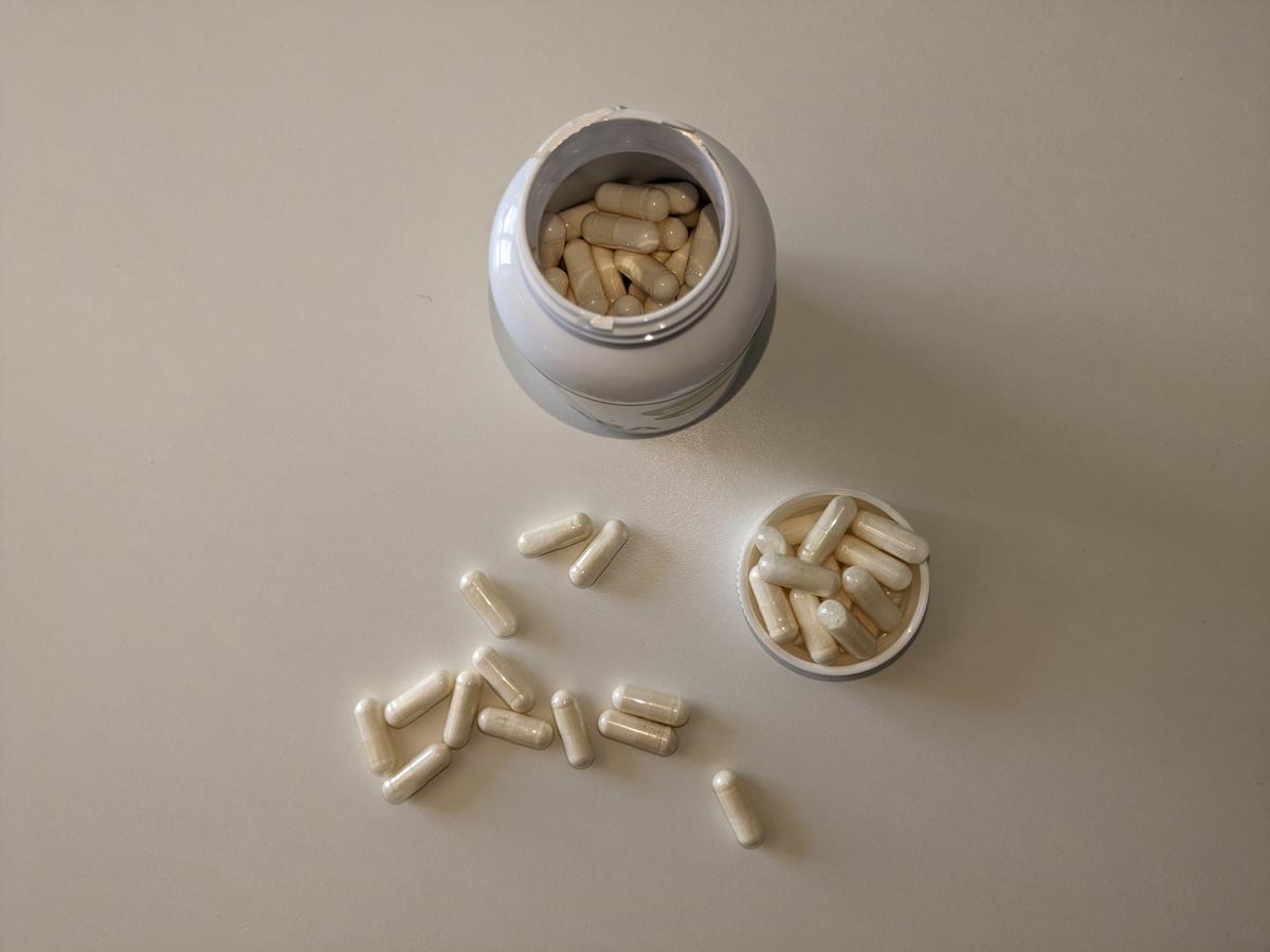 Öppen burk ovanifrån med GABA-kapslar utspridda på bordet, foto från vårt test