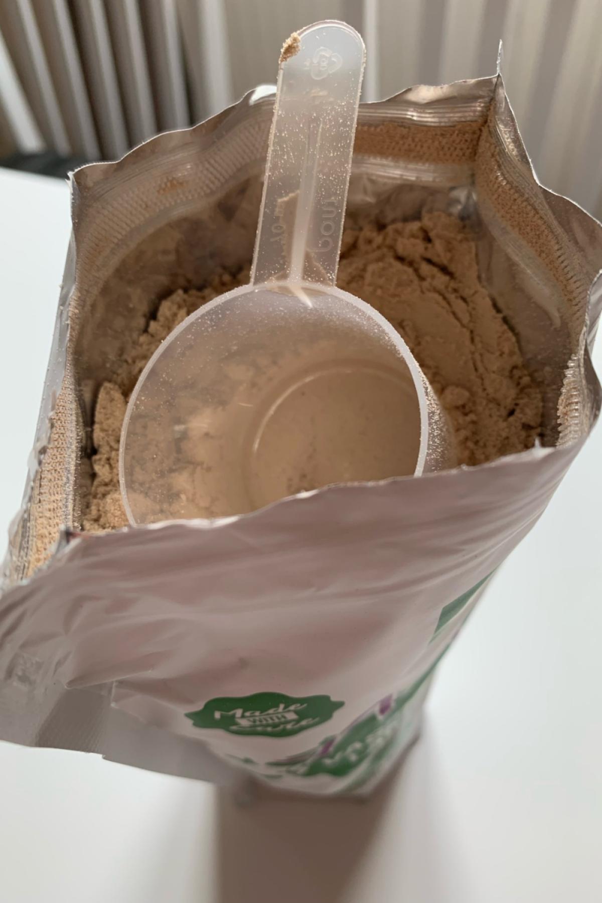 Öppen påse med skopa i chokladpulvret Healthwell Active Vassleprotein Laktosfri foto från vårt test
