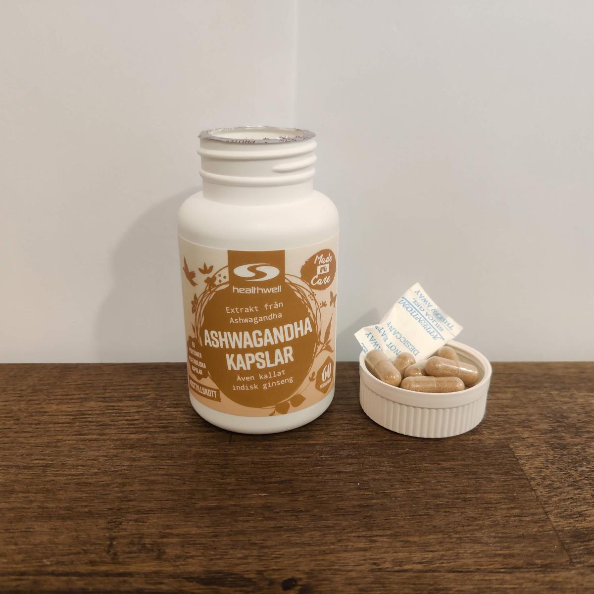 Healthwell Ashwagandha Extrakt och ljusbruna kapslar på bänkskiva, taget av oss under testet