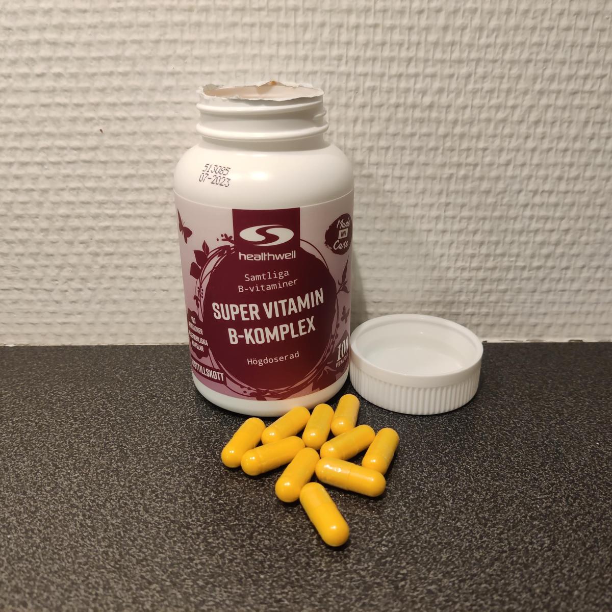 Healthwell Super Vitamin B-komplex fotograferad av oss under testet, öppnad burk med gula kapslar på bänkskiva