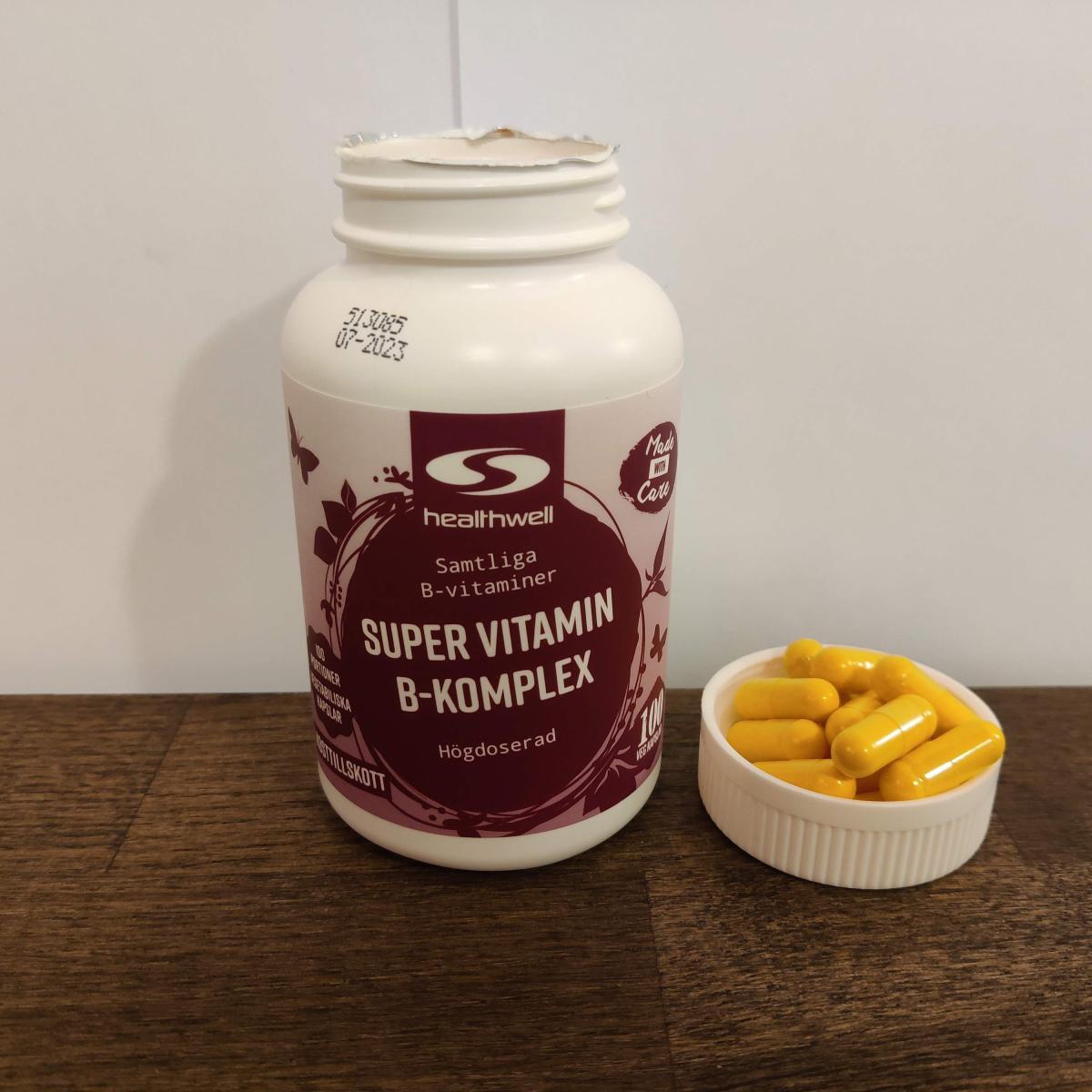 Healthwell Super Vitamin B-komplex på träbord med kapslar bredvid burken, från vårt eget test