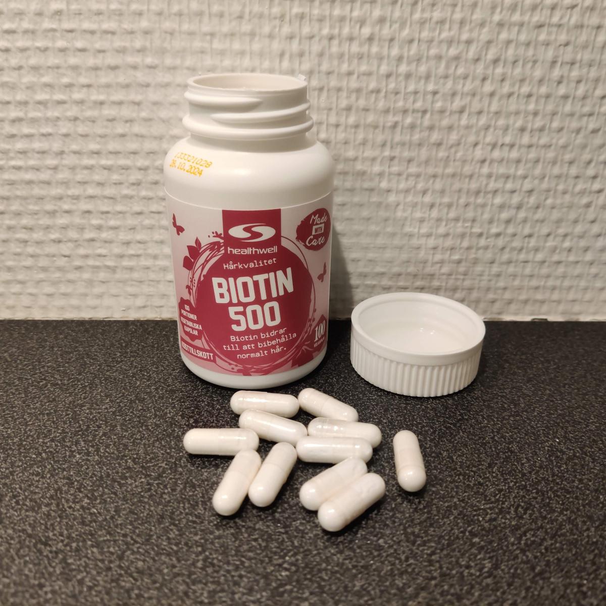 Healthwell Biotin 500 öppnad burk med kapslar på mörk bänk, foto taget av oss under testet