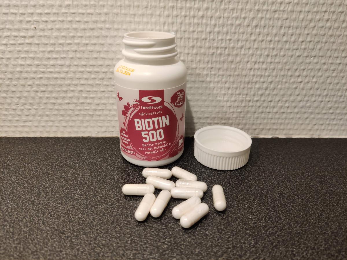 Healthwell Biotin 500 öppnad burk med kapslar på mörk bänk, foto taget av oss under testet