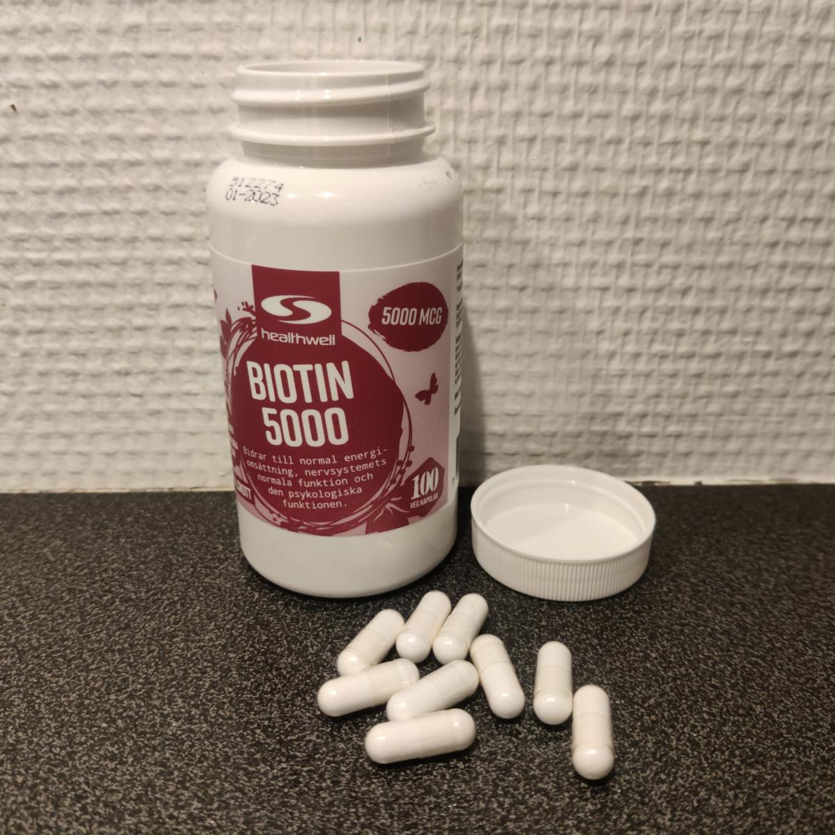 Healthwell Biotin 5000 med öppet lock och kapslar på bänkskiva foto av oss