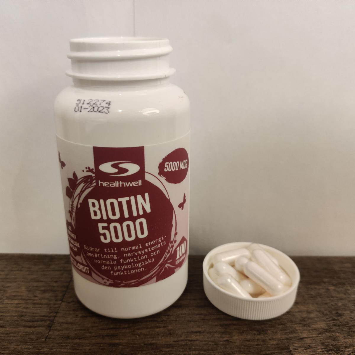 Healthwell Biotin 5000 på träbord med kapslar nära foto av oss