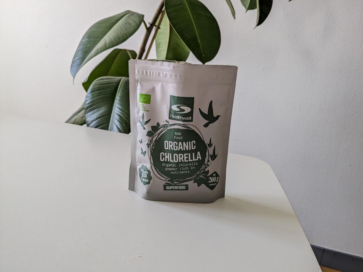 Healthwell Organic Chlorella 200 g på vårt bord under testet med växt i bakgrunden