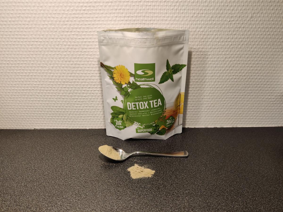 Healthwell Detox Tea med tesked pulver framför påsen, foto taget av oss