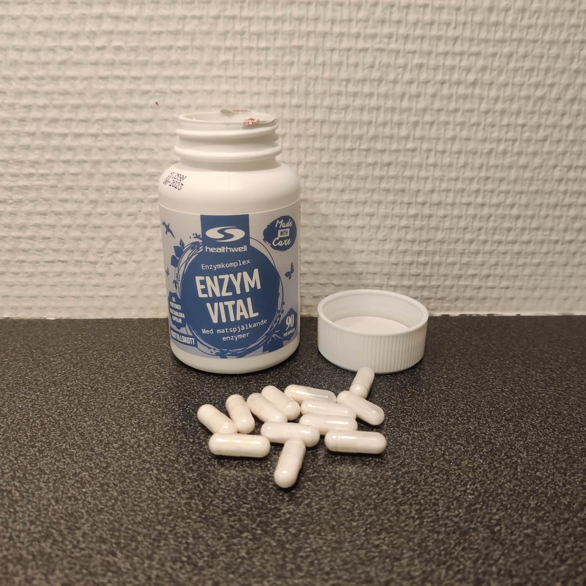 Healthwell Enzym Balans på träbord med kapslar bredvid, taget under test